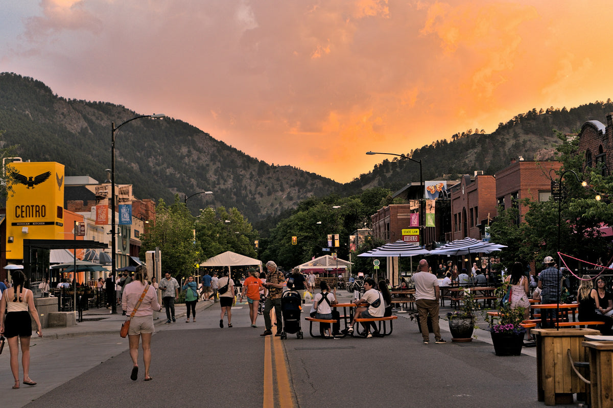 People walking on a Boulder street with mountains behind